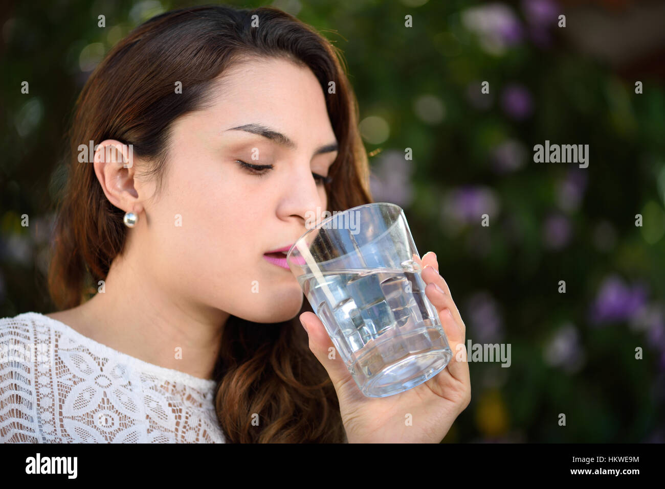 Mädchen Trinkwasser aus Glas im grünen park Stockfoto