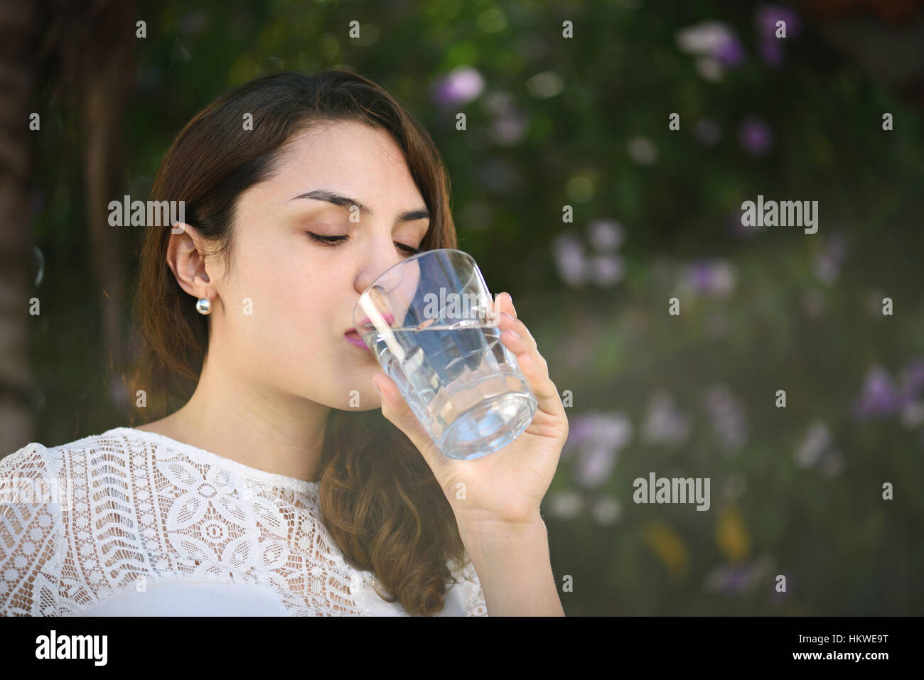 Hispanic Frau Trinkwasser im Licht der Sonne in grünen park Stockfoto