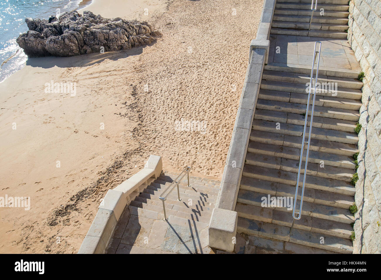zwei Flüge der Treppe einen feinsandiger Strand mit einem Felsen am Rand des Wassers Zugriff auf Stockfoto