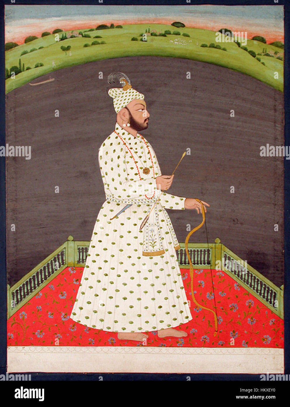 Ein Gemälde von Bishan Singh, dargestellt auf einer Terrasse am See mit Bogen und Pfeil. Das Bild zeigt seine traditionelle Kleidung und Haltung und symbolisiert seine Bereitschaft und Stärke in dieser historischen Umgebung. Stockfoto