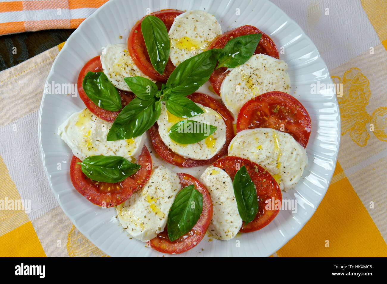 Tomaten und Büffel Mozzarella Caprese-Salat auf bunte Küchentücher - italienisches Rezept zubereitet serviert in weiße Schale - Ansicht von oben - Sommer-Salat Stockfoto