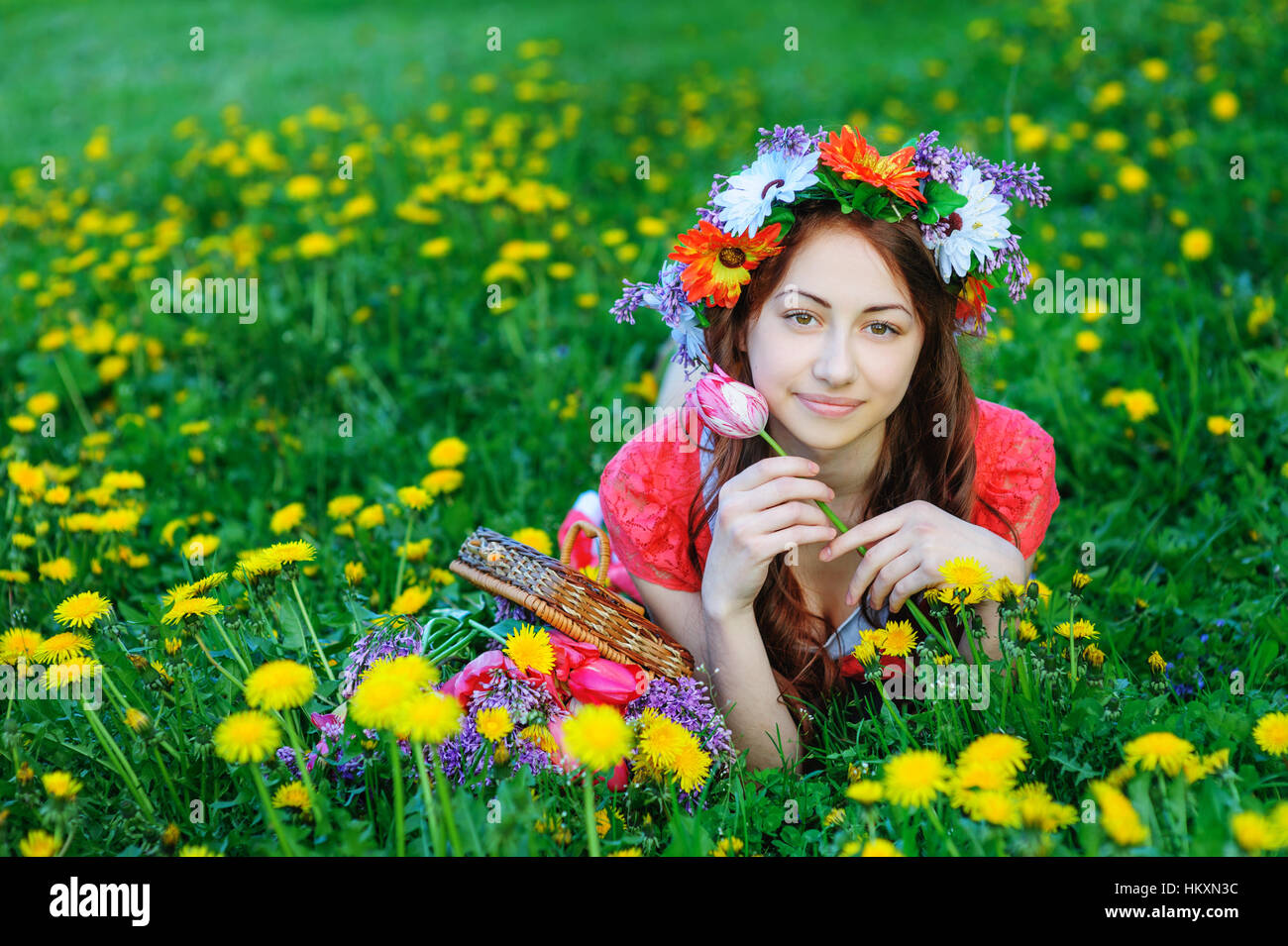 junge Frau in einem roten Kleid auf dem Rasen in der Wiese liegend Stockfoto