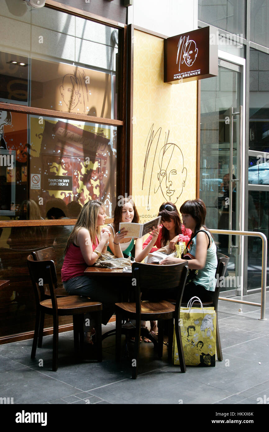 Junge Menschen sitzen an einem Tisch vor dem Cafe Max Brenner, Studium der Speisekarte, Melbourne, Victoria, Australien Stockfoto