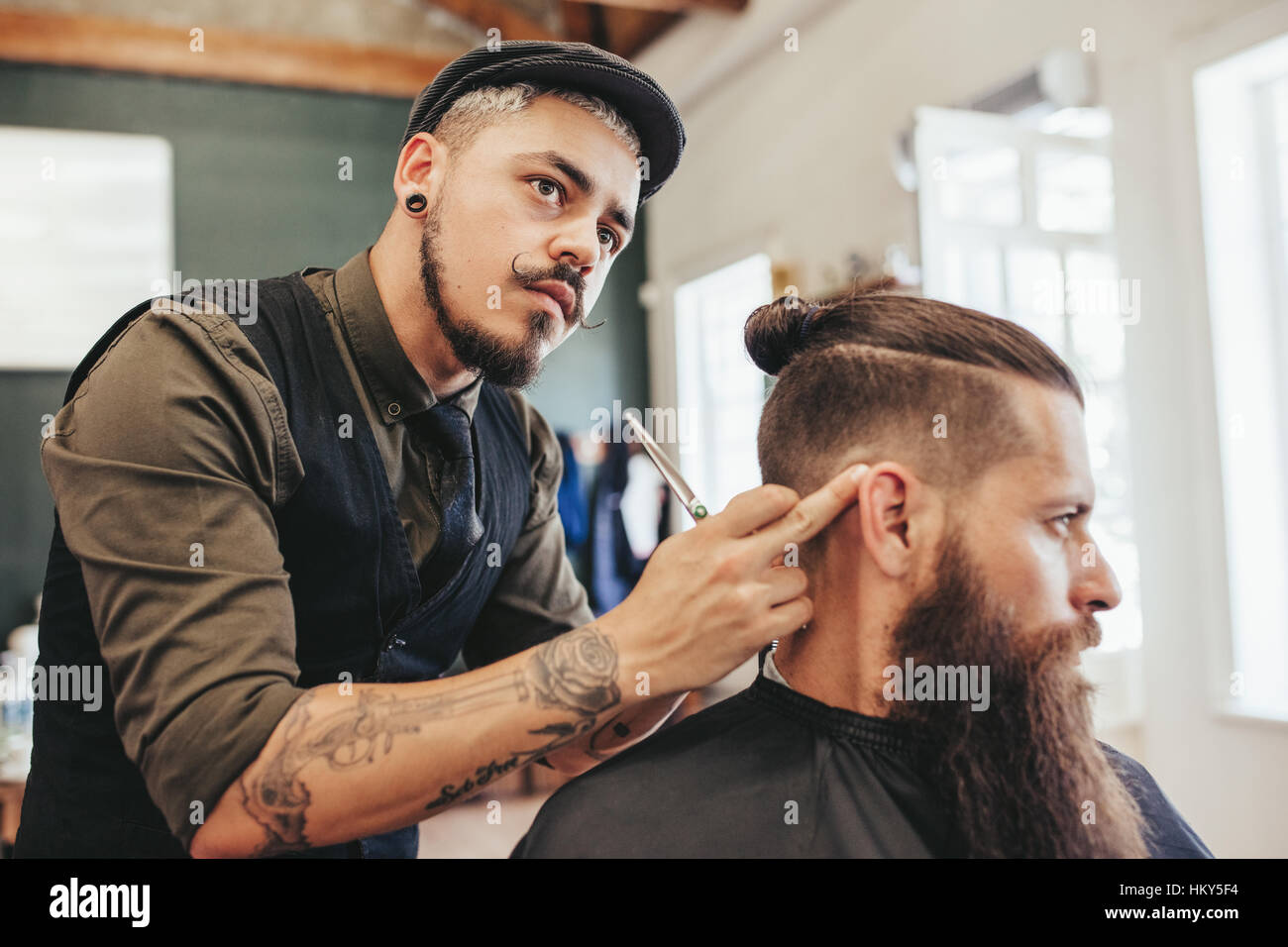 Barbier Überprüfung Symmetrie der Haarschnitt seines Mandanten. Bärtiger Mann immer trendigen Haarschnitt von Friseur im barbershop Stockfoto