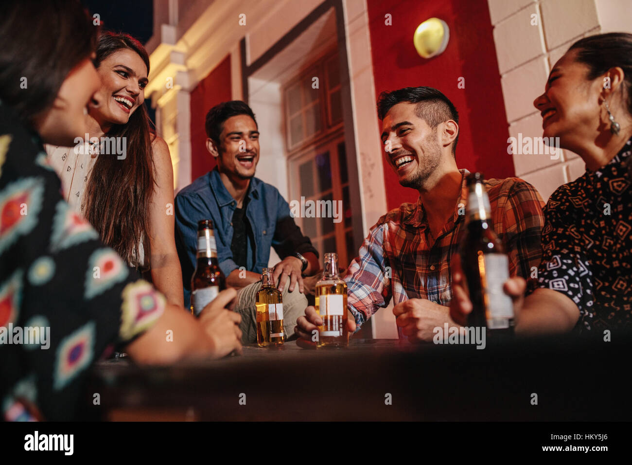 Gruppe von Freunden an einem Tisch auf dem Dach Party mit Bier. Junge Menschen auf Dach mit Getränken. Stockfoto
