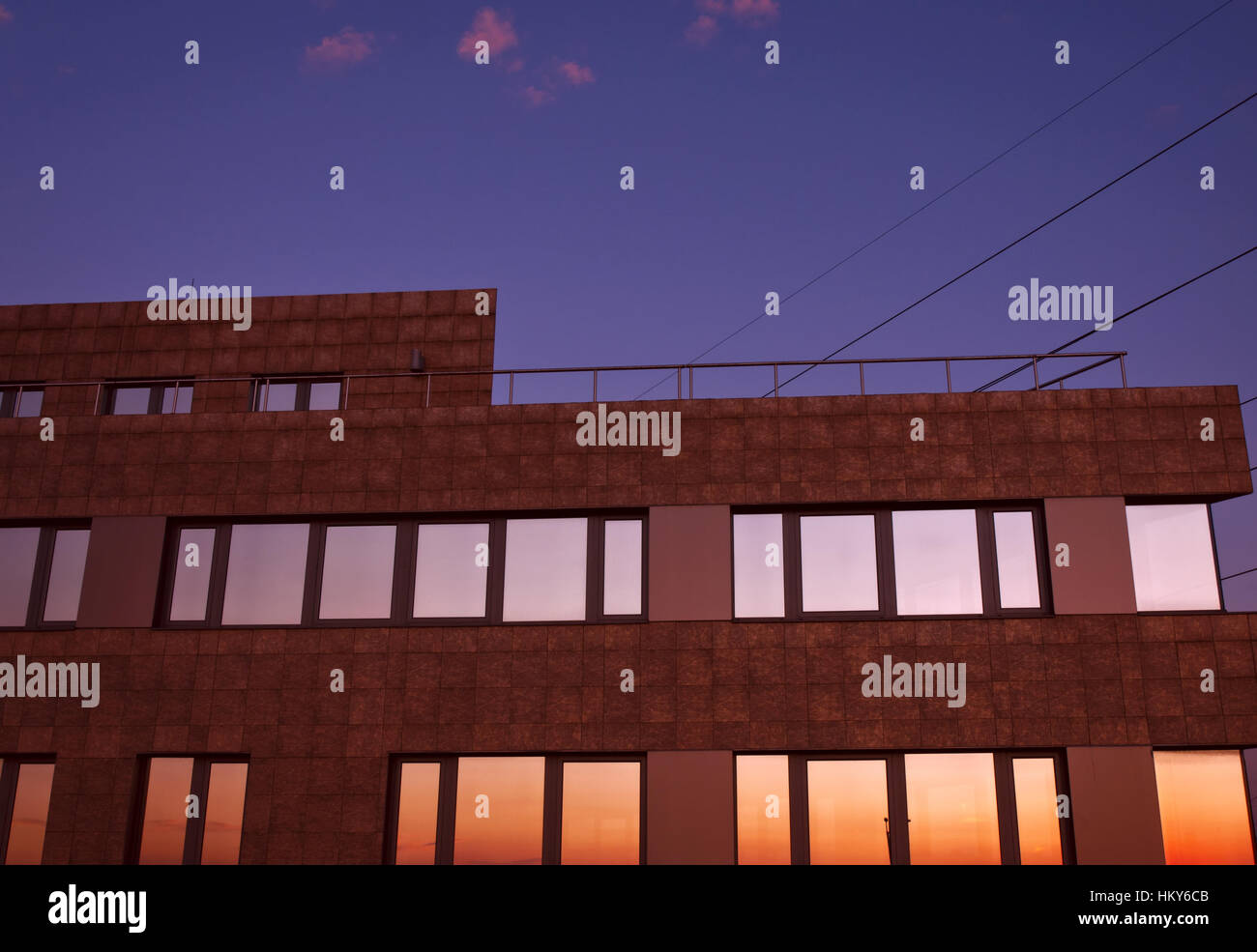 Gebäude in der Dämmerung mit bunten Reflexen in den Fenstern gegen den dunkelvioletten Himmel und die rosa Wolken Stockfoto