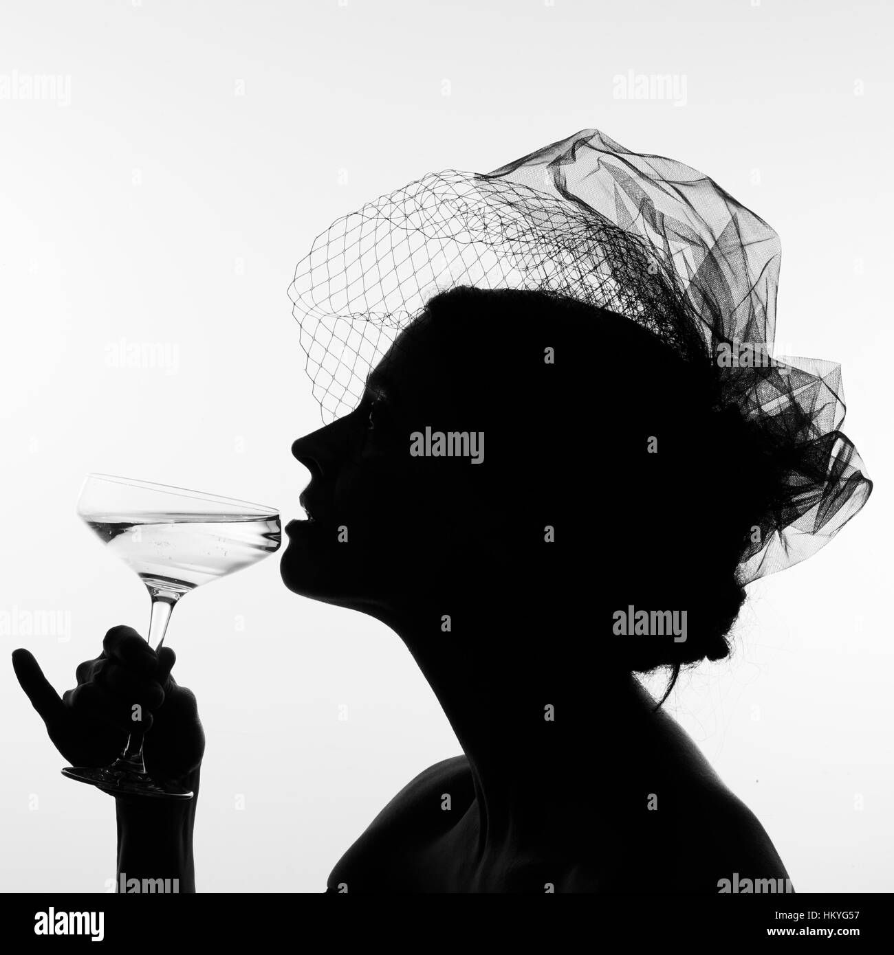 Silhouette einer Frau in einem Schleier schlürfen Champagner aus einem Coupé. Stockfoto
