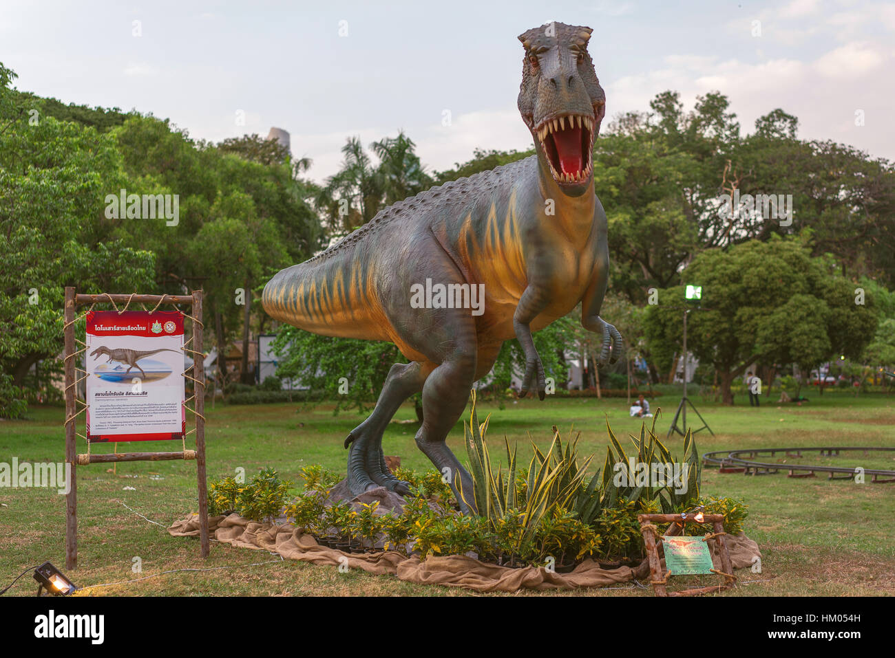 Dinosaurier im Park mit grünem Rasen und Bäumen Stockfoto