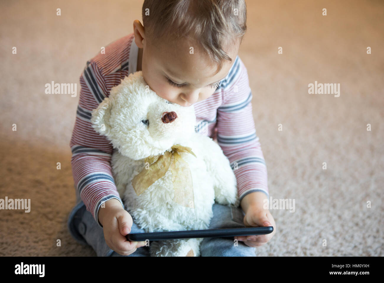 Kleines Kind junge hält einen Teddy-Bären während des Spielens mit Tablet-Computer. Stockfoto