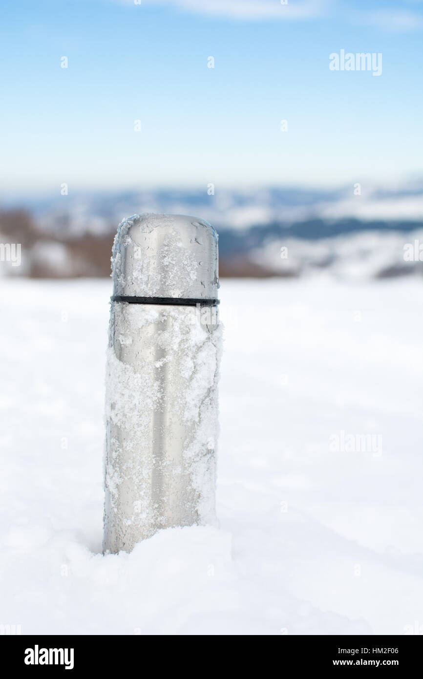 Metall Thermoskanne im Schnee auf einem verschneiten Berg Stockfoto