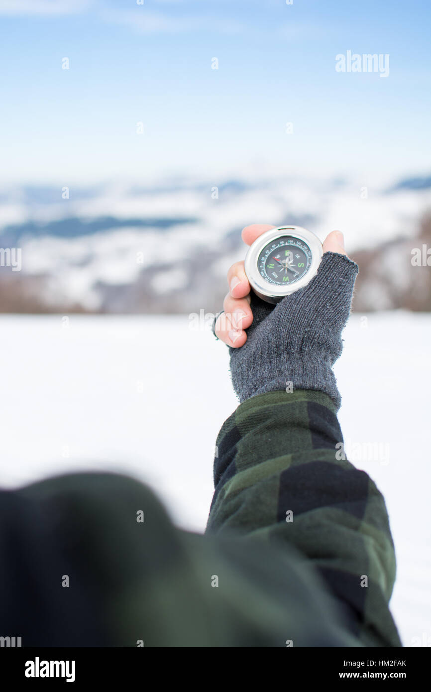 Mann hält einen Metall Kompass auf verschneiten Bergen Stockfoto