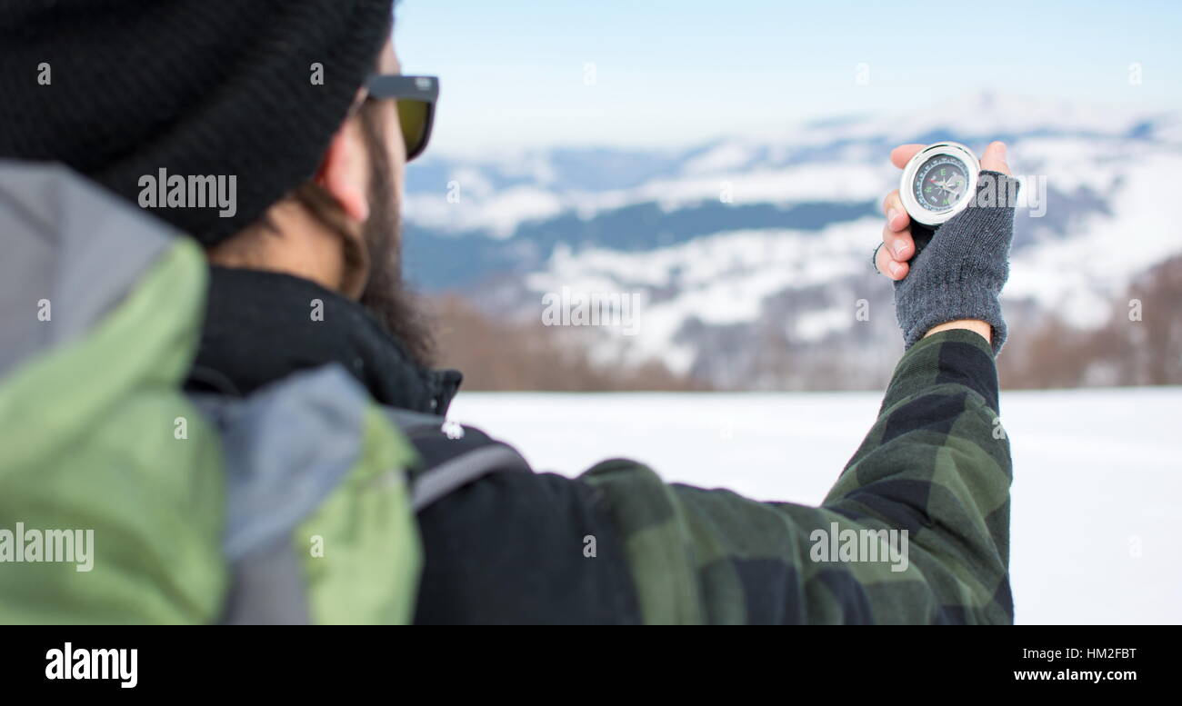 Hipster-Mann mit einem Kompass auf einem verschneiten Berg Stockfoto