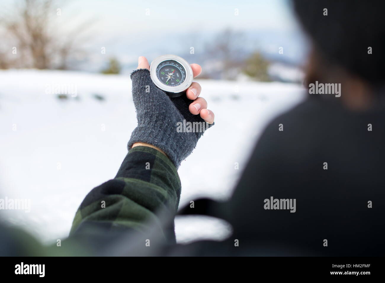 Mann hält einen Metall Kompass auf verschneiten Bergen Stockfoto
