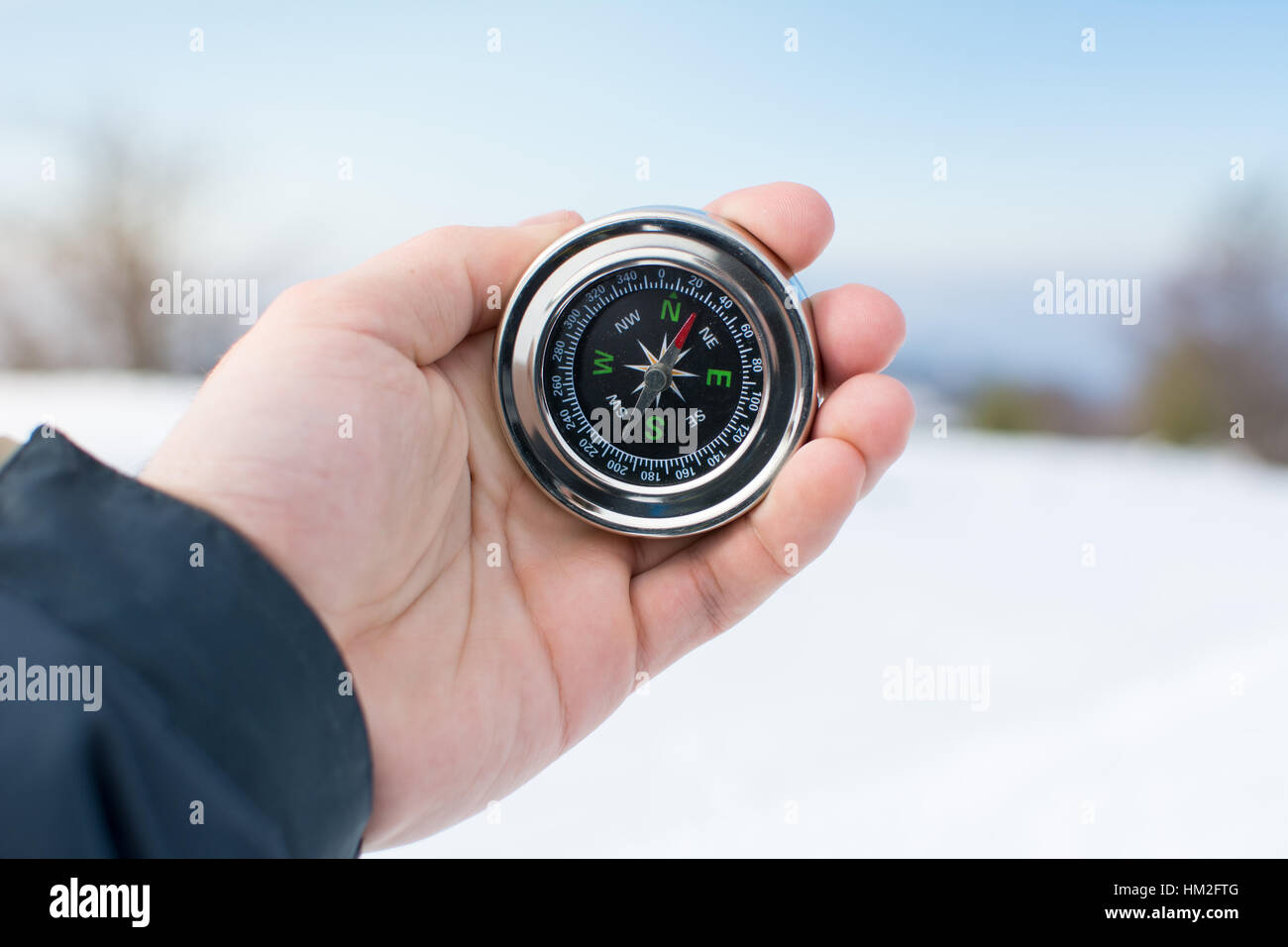 Mann mit einem Kompass auf einem verschneiten Berg Stockfoto