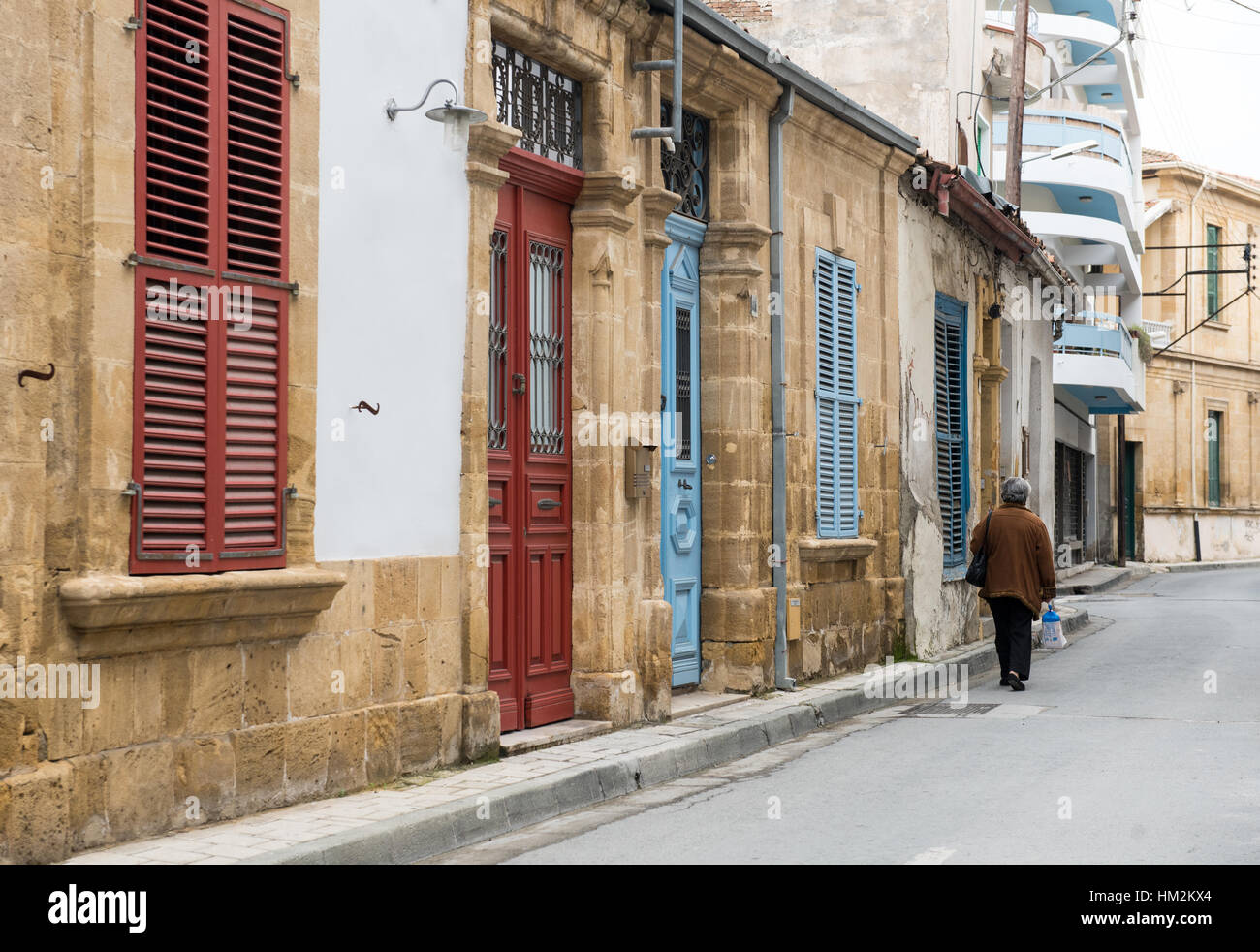 Ältere Frau hält einen Beutel mit Lebensmittel, die zu Fuß in einer Nachbarschaft in den Straßen der Altstadt von Nikosia in Zypern Stockfoto