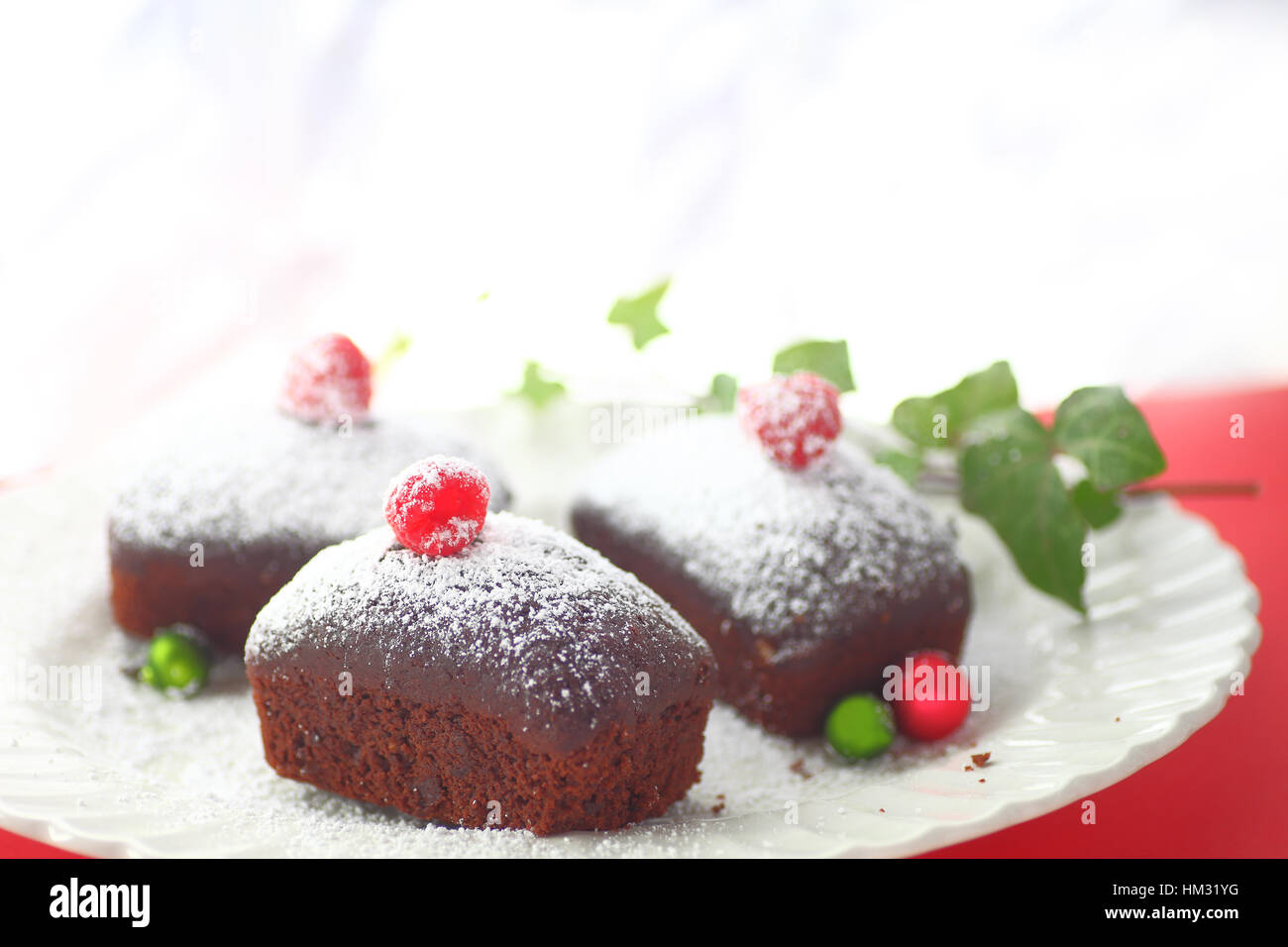 Drei Miniatur Schokolade Kuchen mit Puderzucker, frische Himbeeren und kleinen Weihnachtskugeln Stockfoto