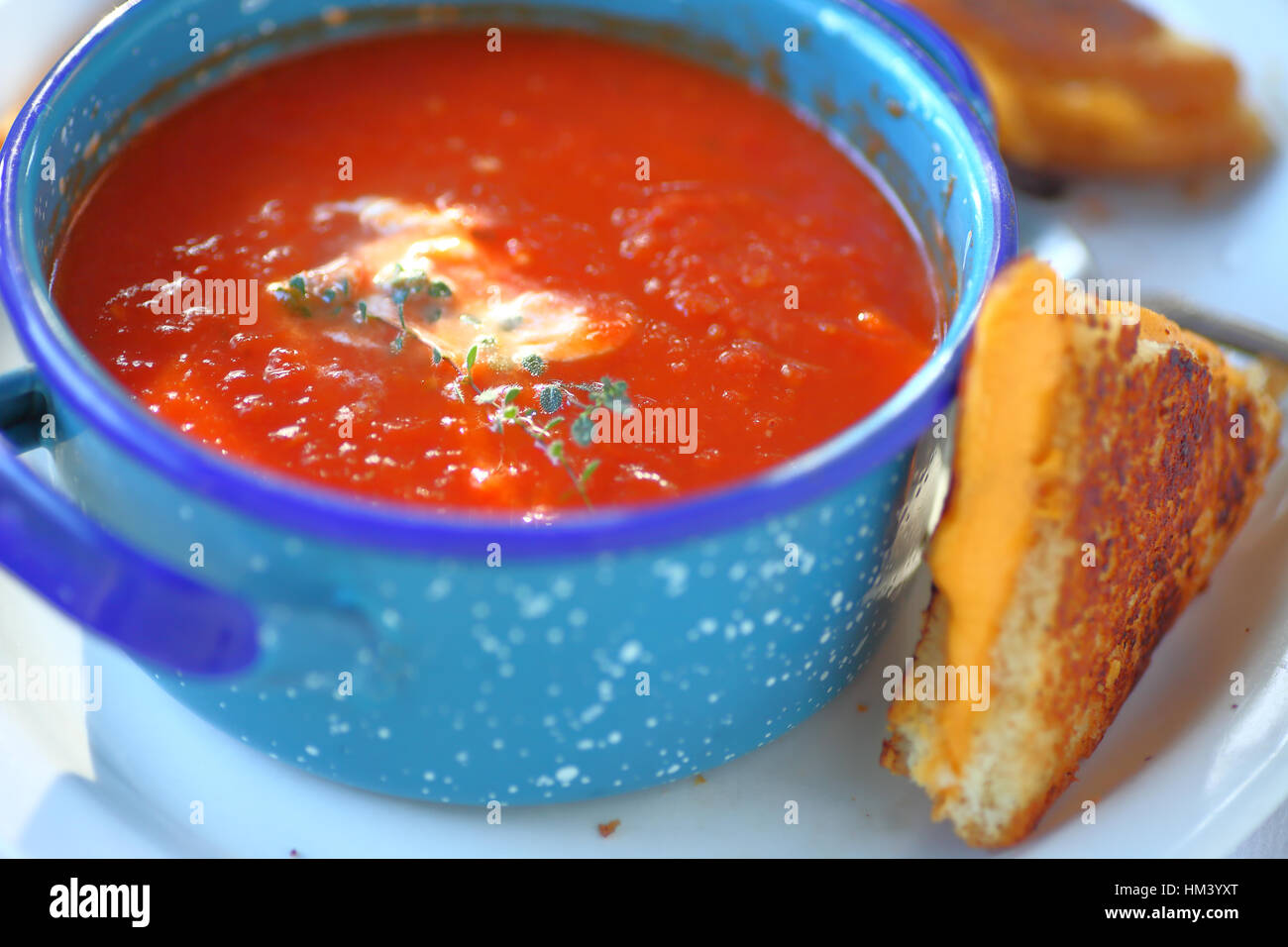 Tomatensuppe mit frischem Thymian in einen Topf Schüssel mit einem Käse-Sandwich in Dreiecke schneiden Stockfoto