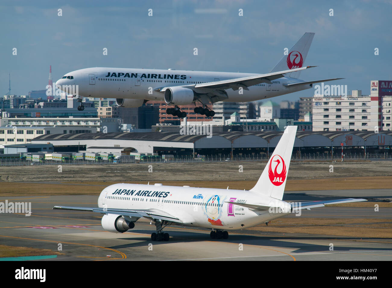 Ein Japan Airlines Boeing 767 wartet für den Start, während eine Firma Boeing777 am Flughafen Fukuoka, Japan landet Stockfoto