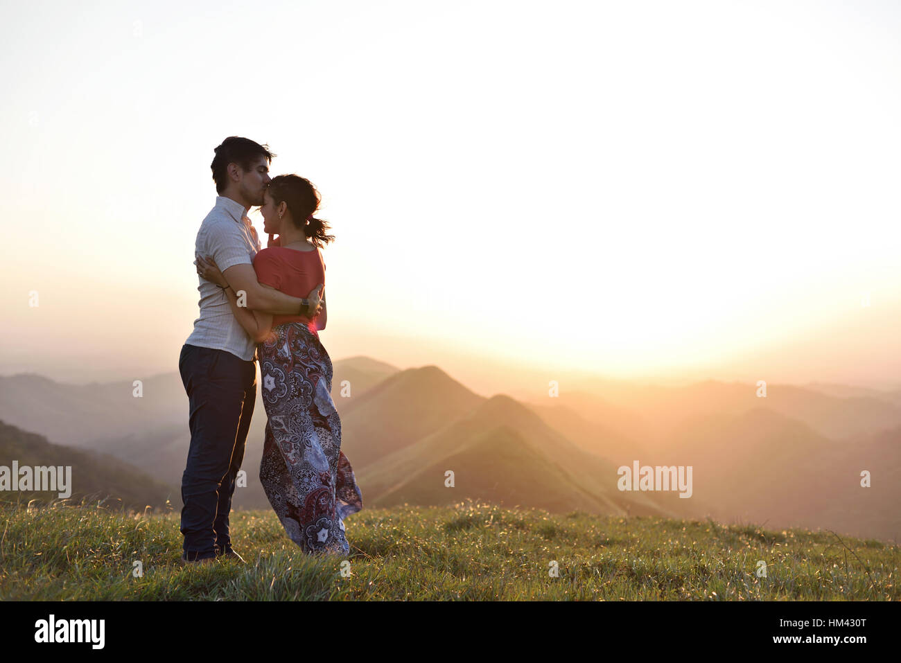 Paar in Liebe treffen Sonnenuntergang in grüne Hügel-Landschaft Stockfoto