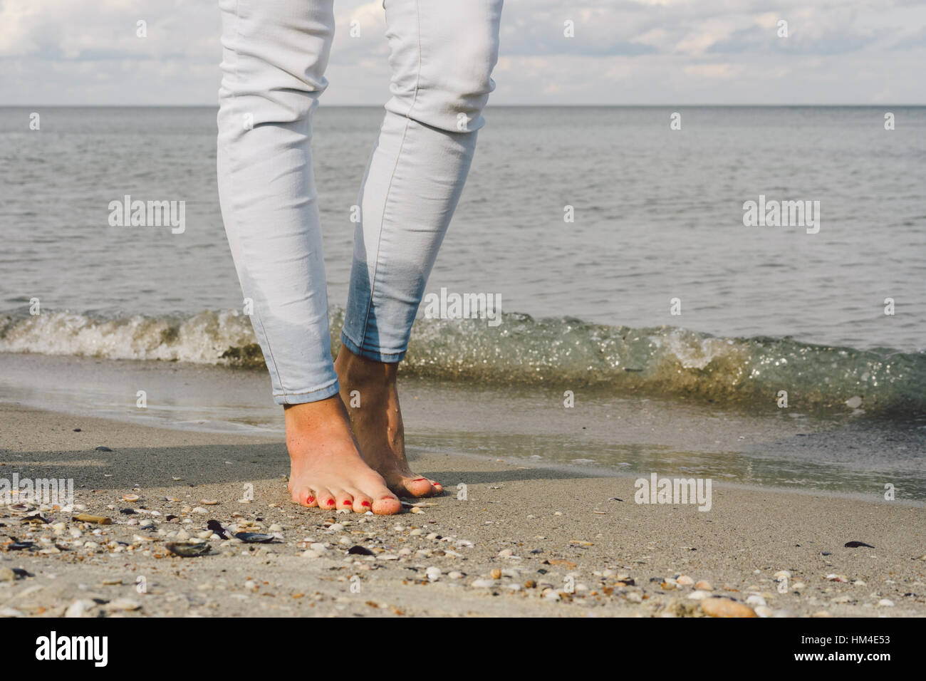 Weibliche Füße in Jeans barfuß gehen auf das Wasser des Meeres am Strand  Stockfotografie - Alamy