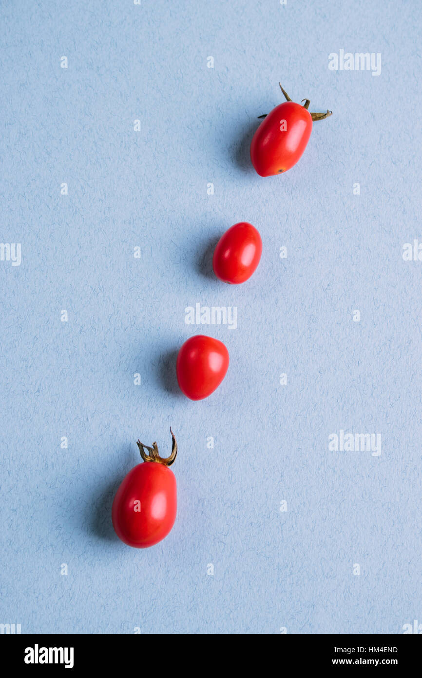 Rote Cherry-Tomaten auf a blaue Tabelle, flache Ansicht, vertikale Rahmung Stockfoto