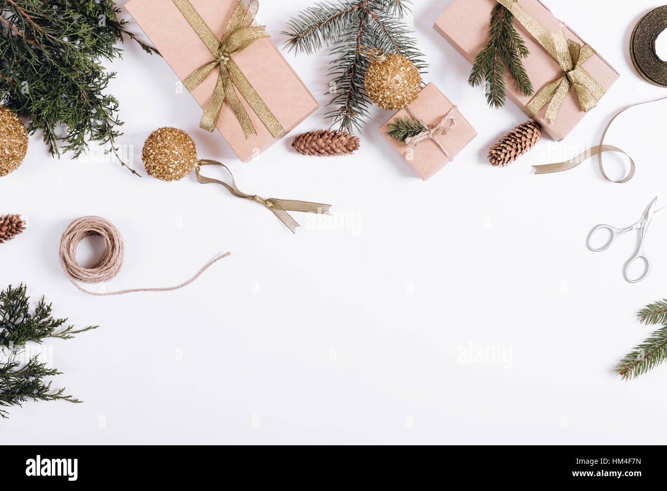 Weihnachts-Dekorationen auf weißem Hintergrund: Zweige der Tanne, Geschenkboxen, Bänder, Spielzeug, Seil, Schere Stockfoto