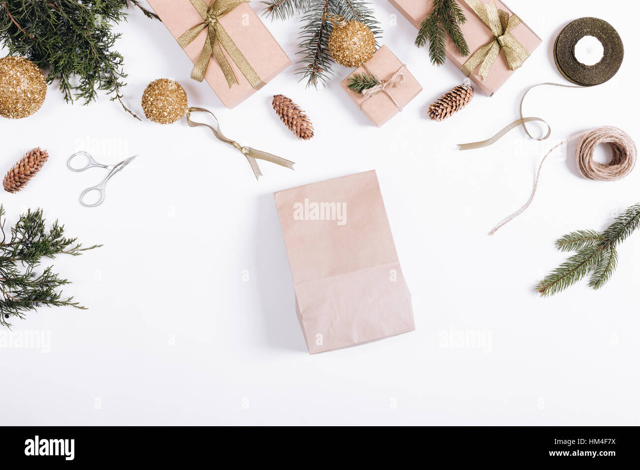 Weihnachts-Dekorationen auf weißem Hintergrund: Papier Tasche, Tannenzweigen, Geschenkboxen, Bänder, Spielzeug, Seil, Schere Stockfoto