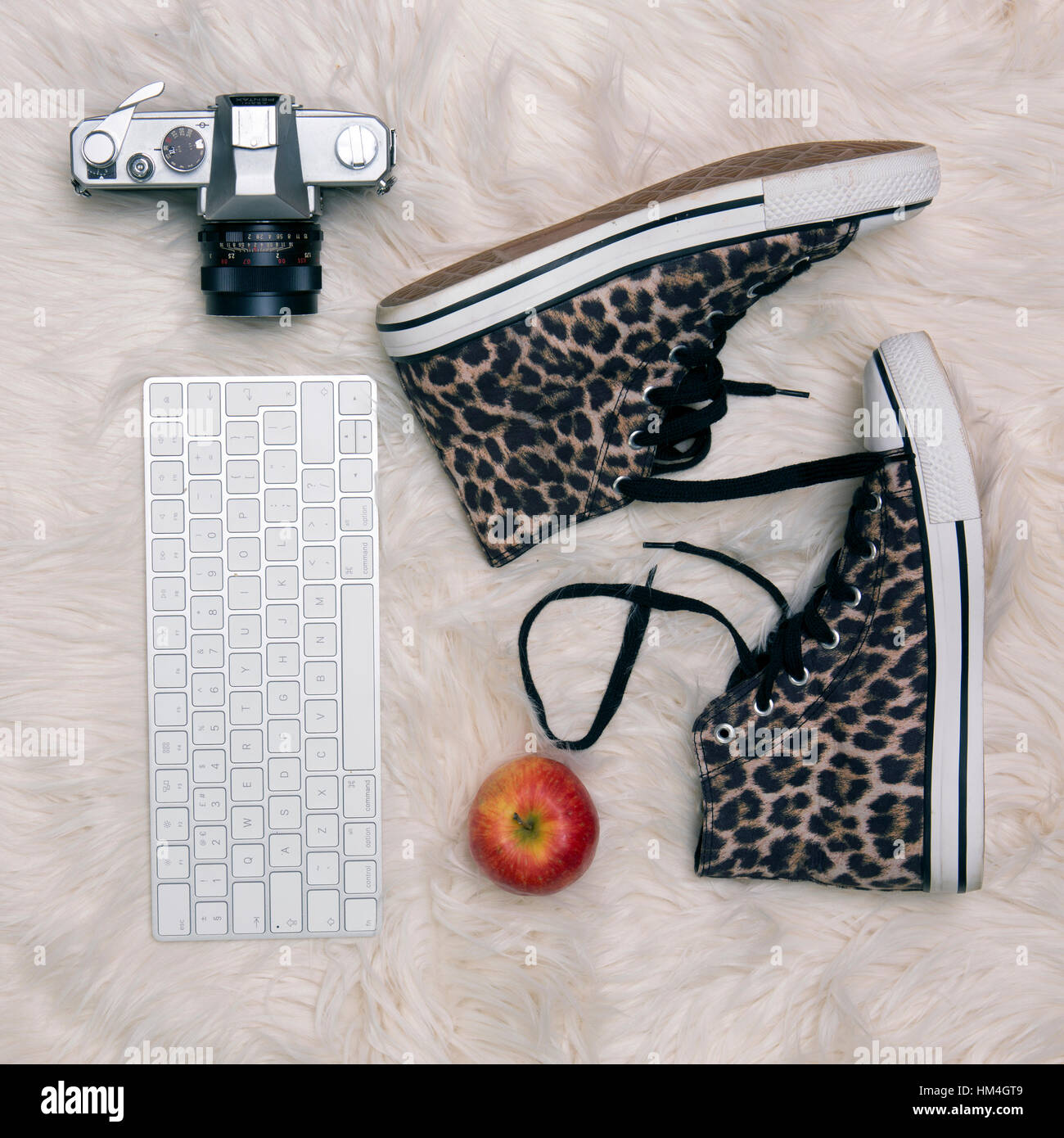 Lebensstil mit Leopard print Stiefel alte Kamera Tastatur und Apple auf einem Fell Teppich flach legen Stockfoto