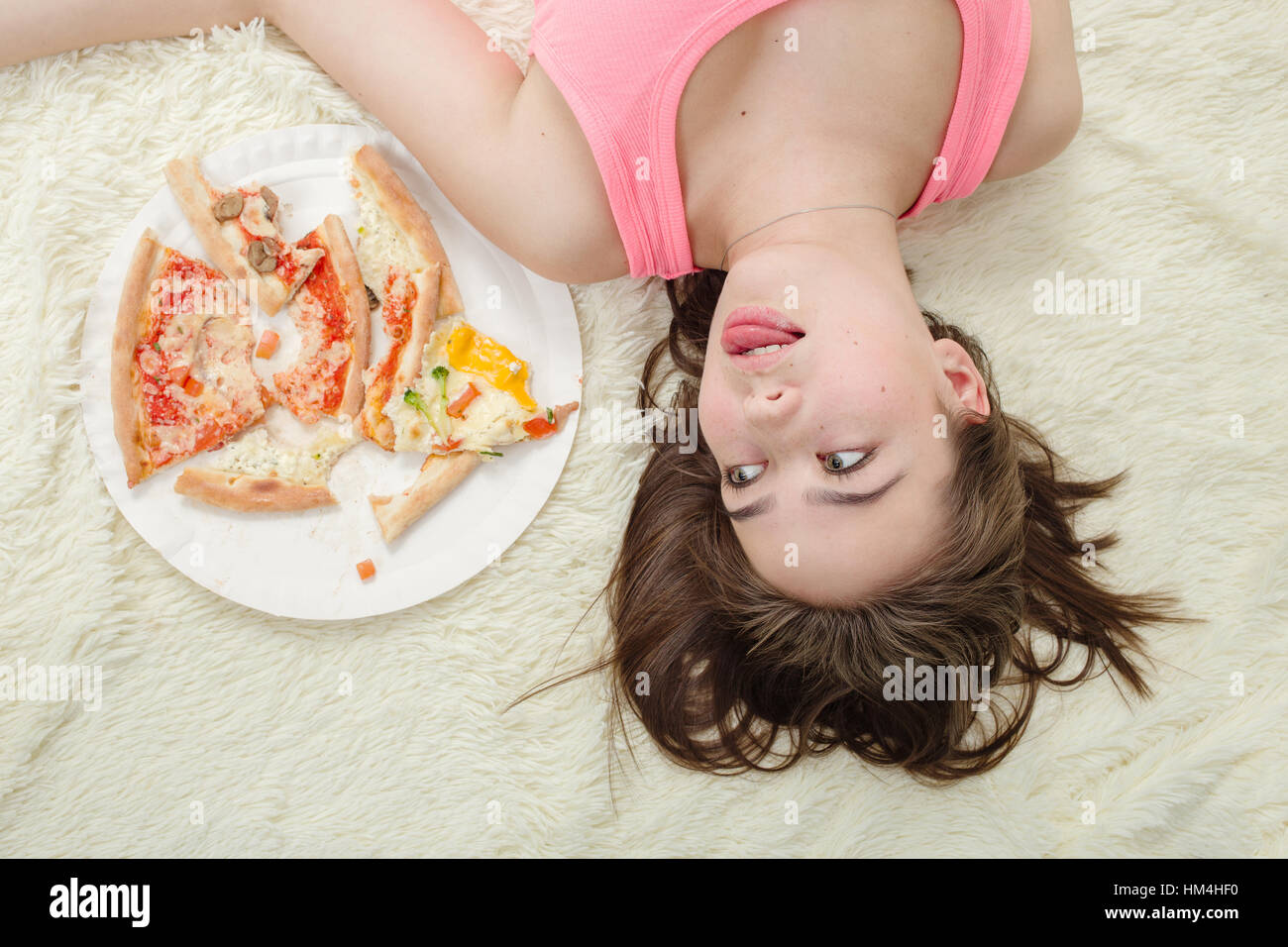 Trauriges Mädchen liegend mit Pizza-Stücke zu viel Essen Stockfoto