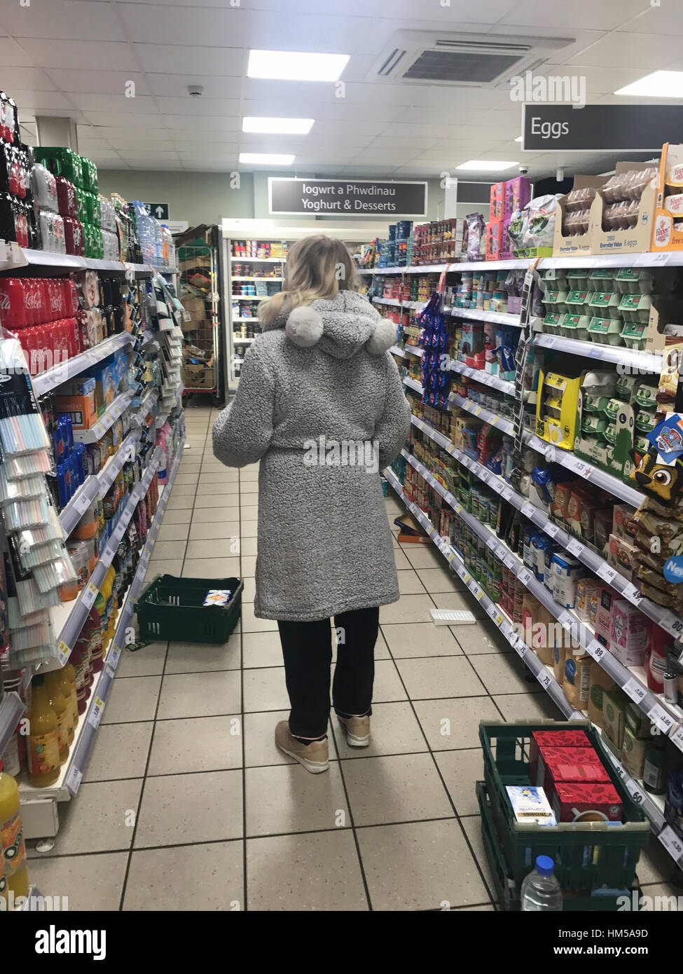 Eine Studentin Frau gesehen einkaufen tragen ihre Pyjammas und Morgenmantel in einem Supermarkt-Geschäft in Cardiff, Südwales, UK. Stockfoto