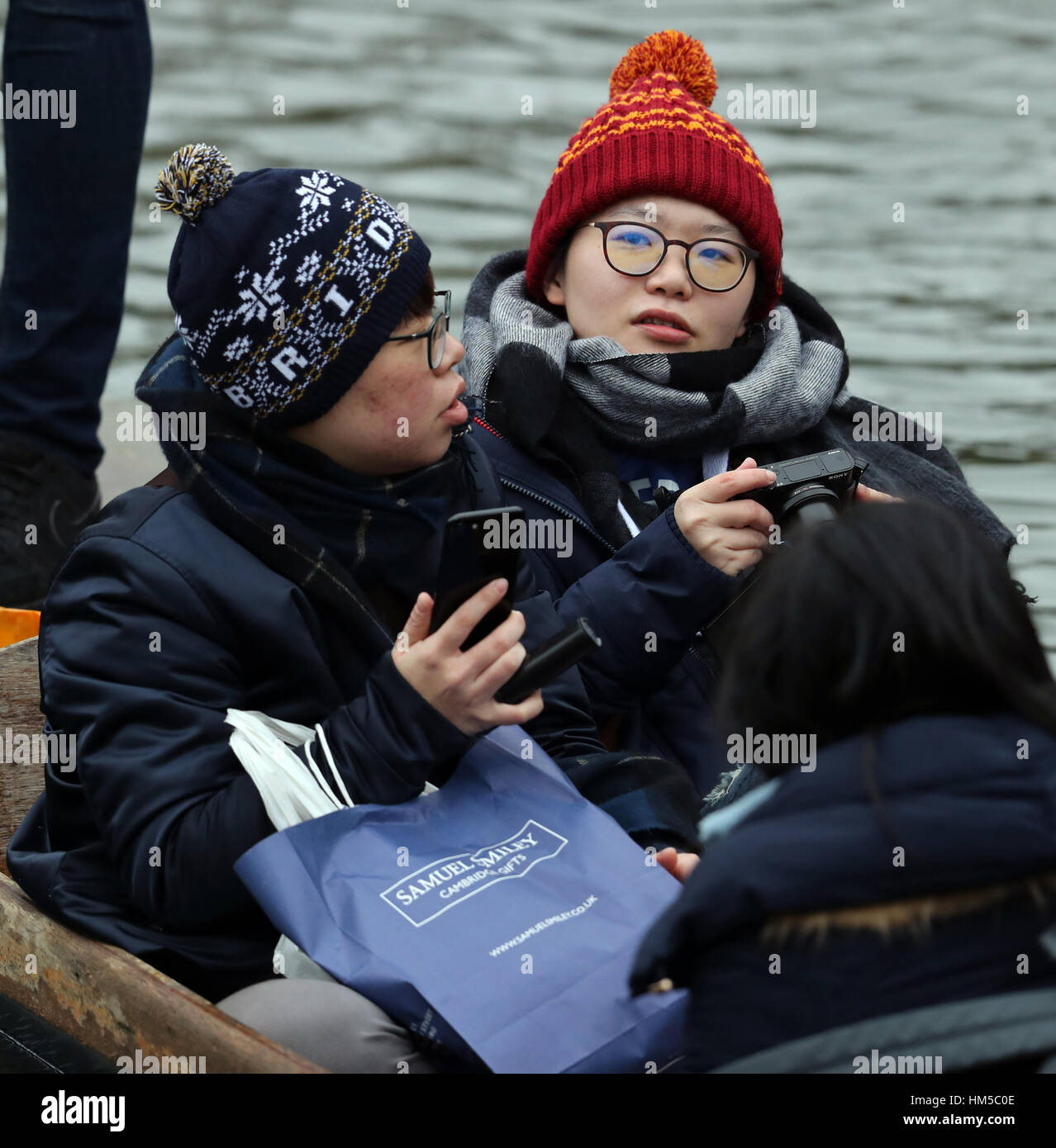 Touristen rap gegen die Kälte, da sie einen Punt entlang des Flusses Cam in Cambridge nehmen. Stockfoto