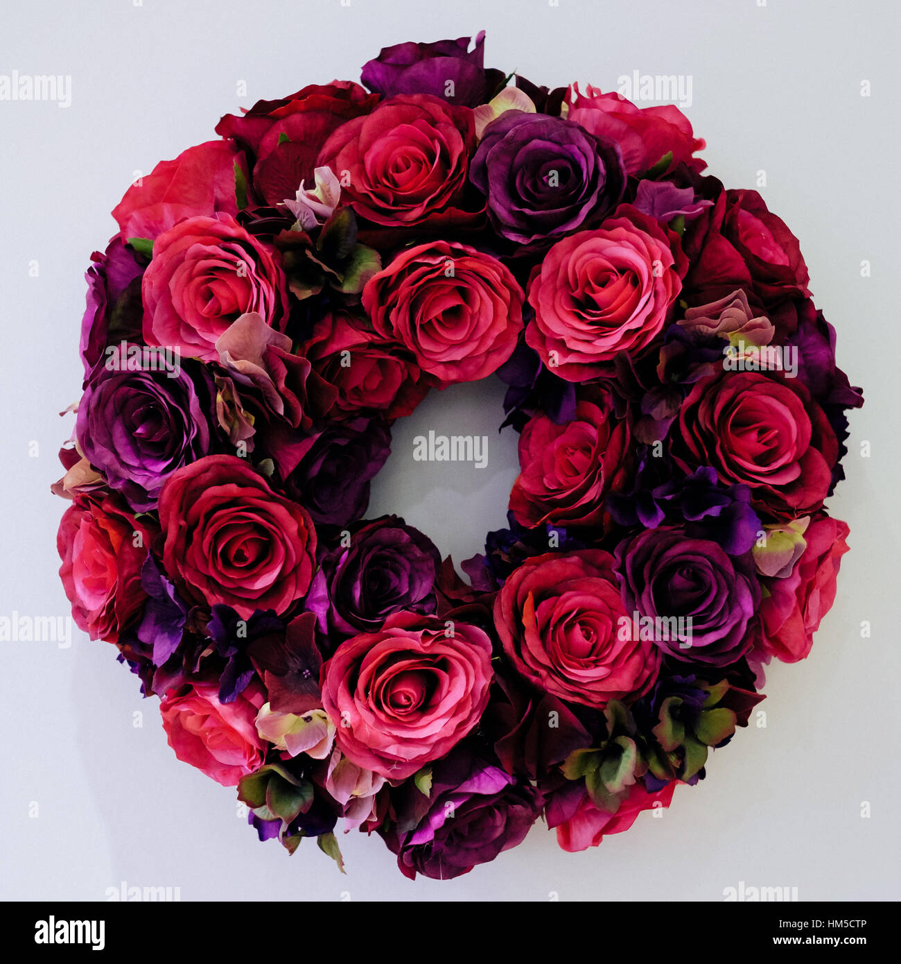 Eine handgefertigte Seidenblume kreisförmigen Kranz hergestellt aus roten und lila Rosen Stockfoto