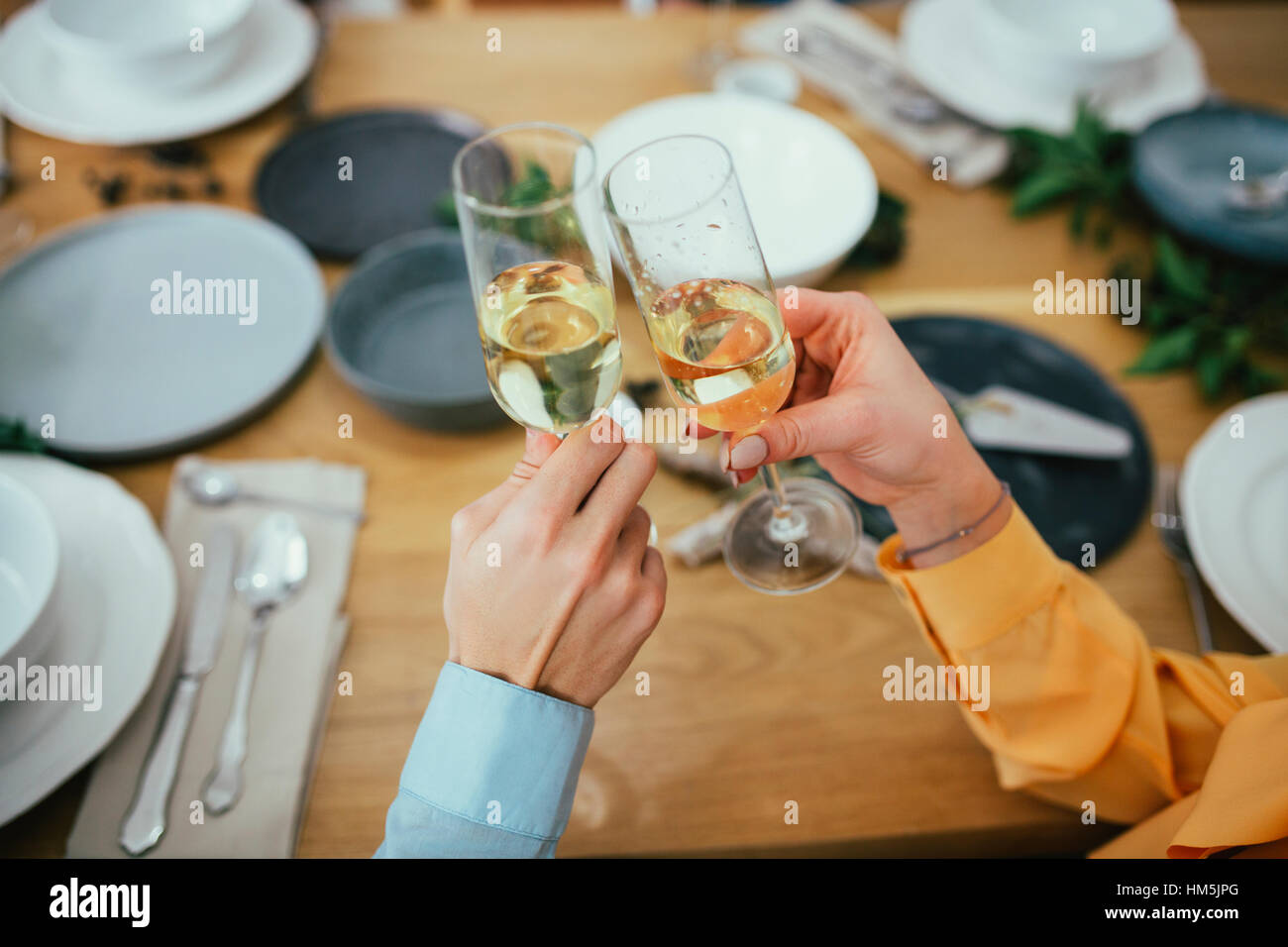 Zugeschnittenes Bild von Freunden Toasten Champagner Flöten beim Sitzen am Esstisch Stockfoto