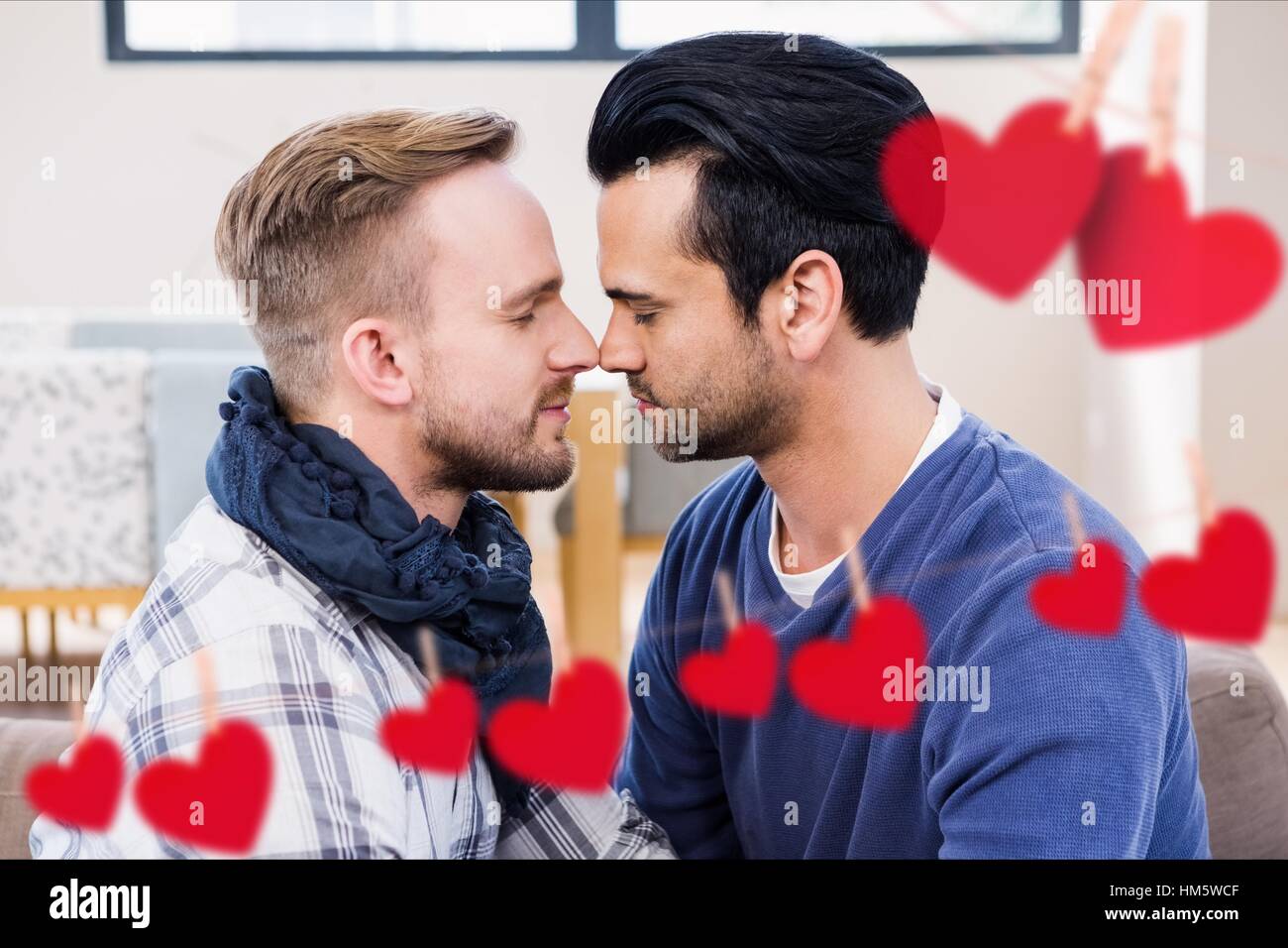 Zusammengesetztes Bild rot hängende Herz und homosexuelle Paare küssen Stockfoto