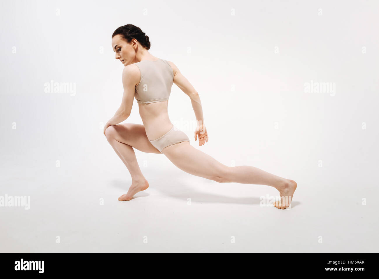Flexile junge Turnerin im weißen farbigen Studio durchführen Stockfoto
