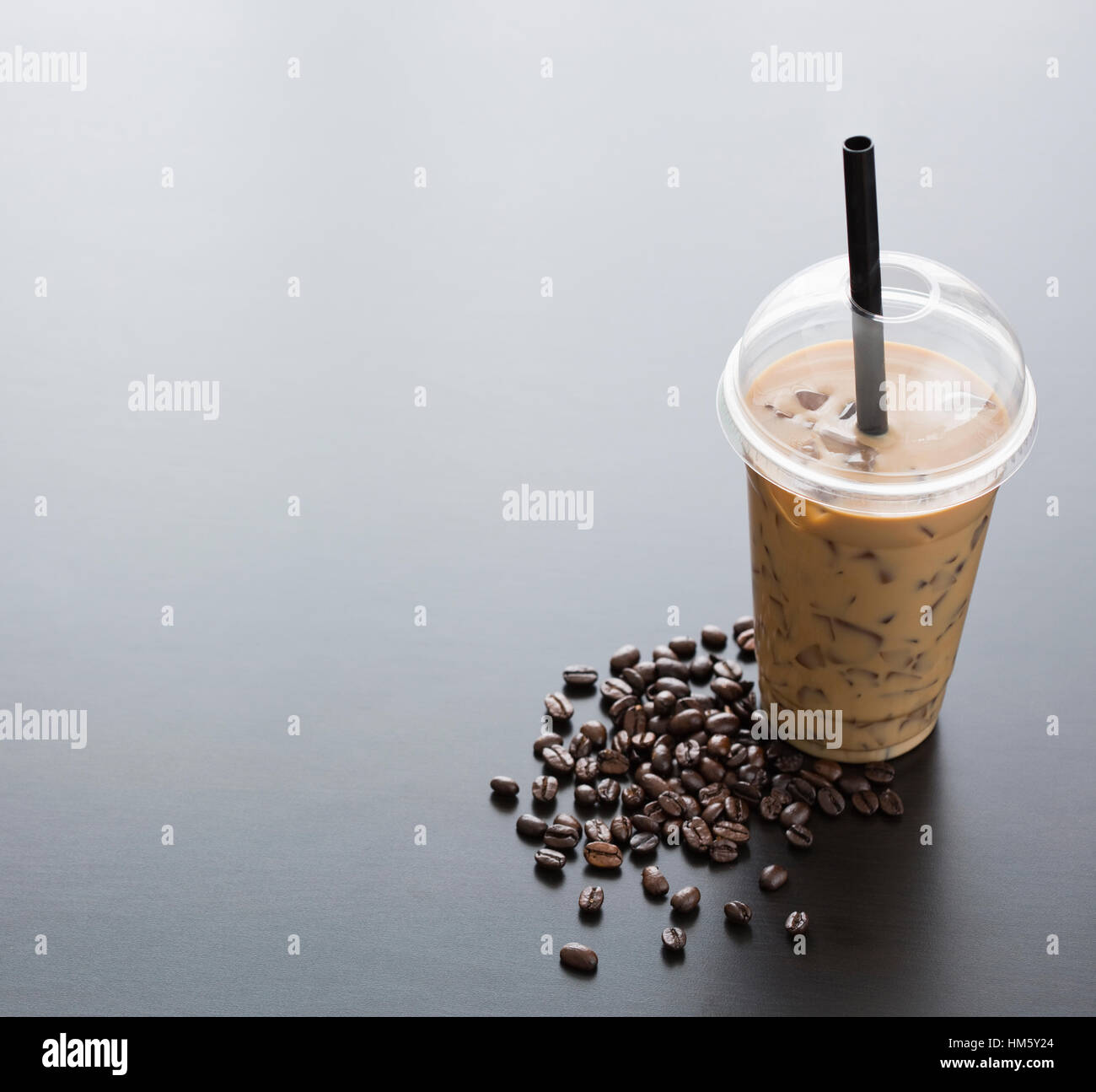 Eiskaffee in Einweg-Cup und Kaffeebohnen auf Tisch Stockfoto