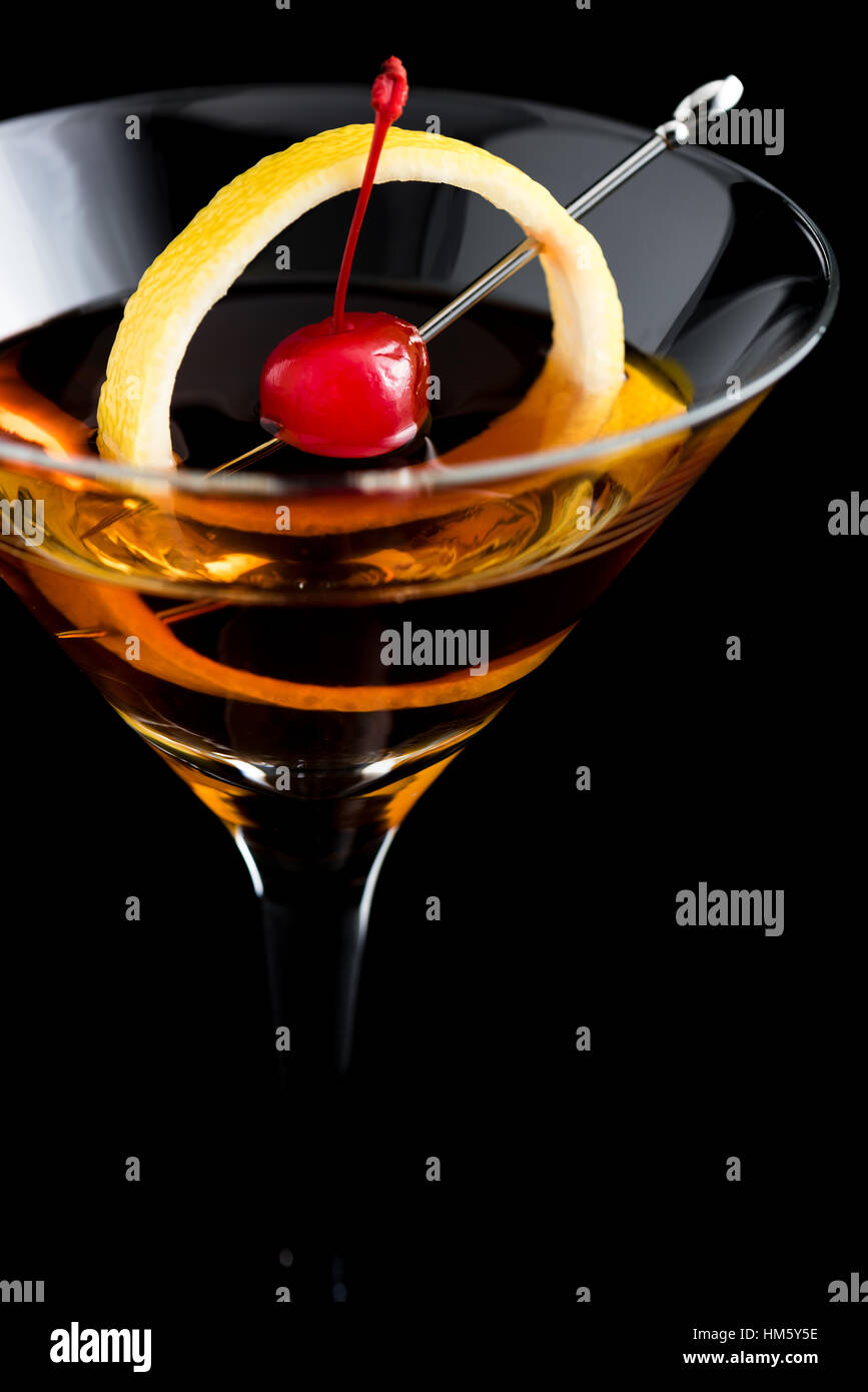 Manhattan cocktail mit Zitrone und Cocktailkirsche auf schwarzem Hintergrund Stockfoto