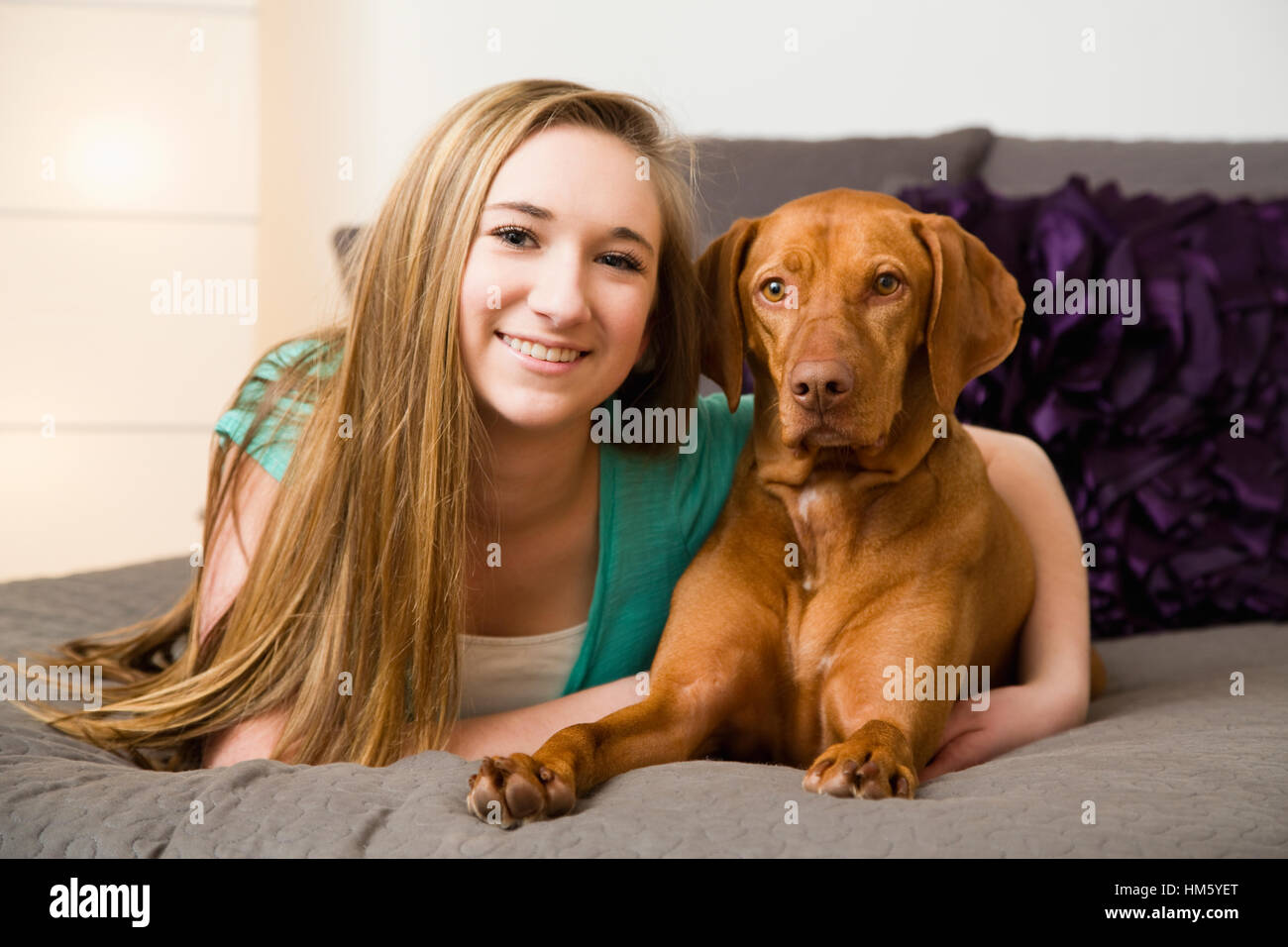 Teenager-Mädchen (16-17) auf Bett liegend mit brauner Vizsla Hund Stockfoto
