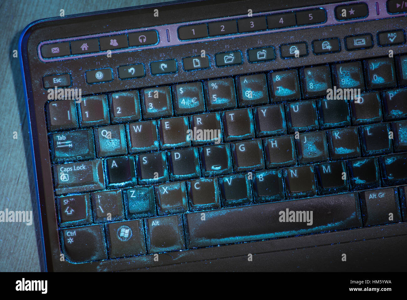 Computer-Tastatur, fluoreszieren im ultravioletten Licht, zeigt schmutzige Tasten und Oberfläche Stockfoto