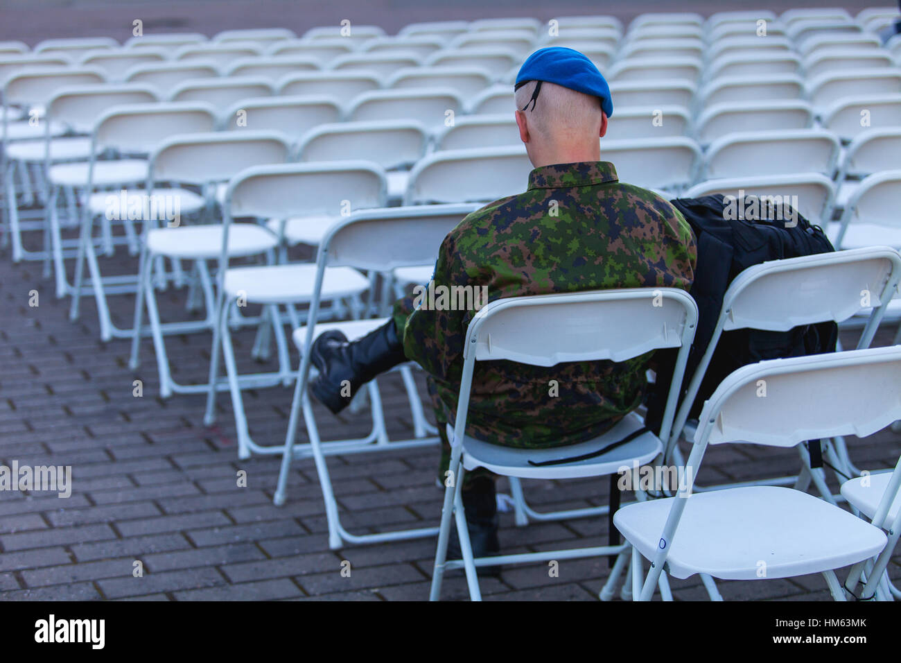 Junger Mann (estnische Soldaten) auf weißen Stuhl sitzt und wartet Konzert Stockfoto