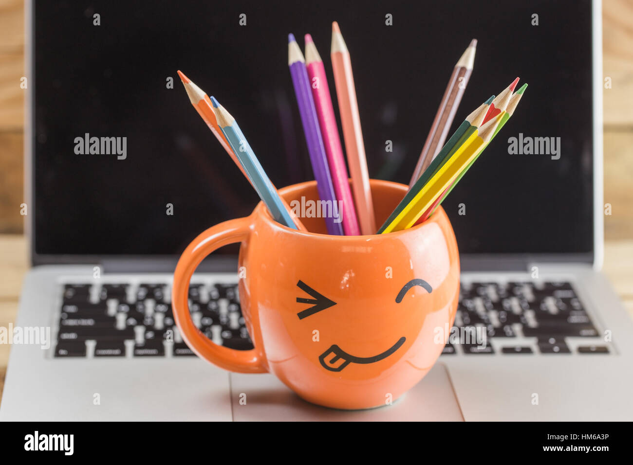 Laptop mit happy Smiley Falten Gesicht Mug und Farbe Bleistift auf Holz Hintergrund, digitale arbeiten kreative Idee mit Idee Digitalkünstler Konzept zufrieden. Stockfoto