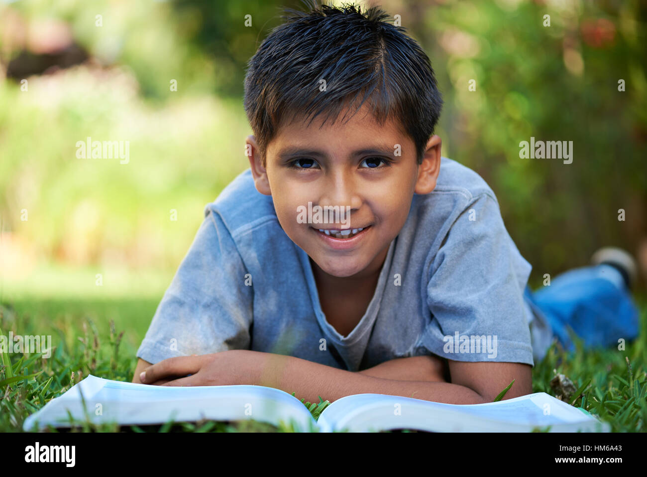 kleiner Junge mit großen Buch lag auf dem grünen Rasen Stockfoto