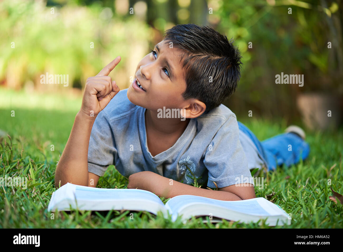kleiner Junge denken auf dem Rasen im Sommerpark Stockfoto