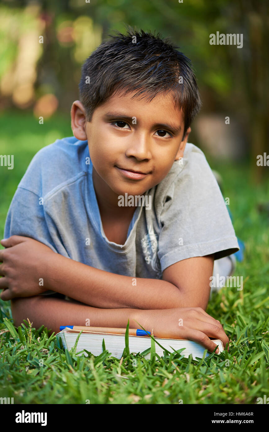 Junge mit Büchern lag auf dem grünen Rasen im park Stockfoto