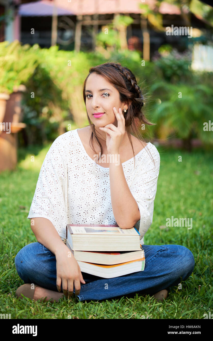 Mädchen denken, was sie im Park mit Bücher studiert Stockfoto