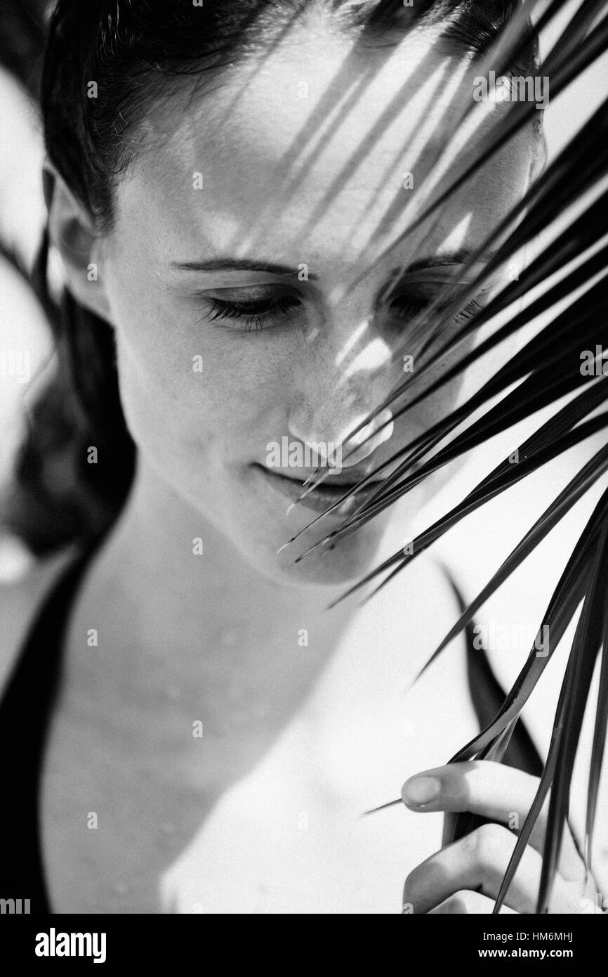 Schatten von einem Palmblatt auf weibliches Gesicht Stockfoto