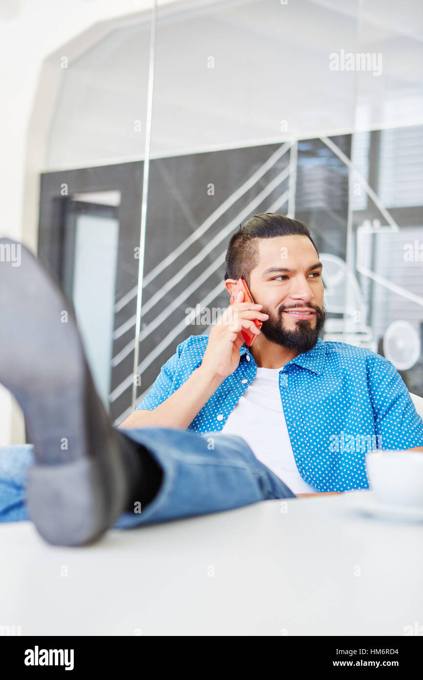 Junger Student als Start-up-Gründer fordert das Telefon im Büro Stockfoto