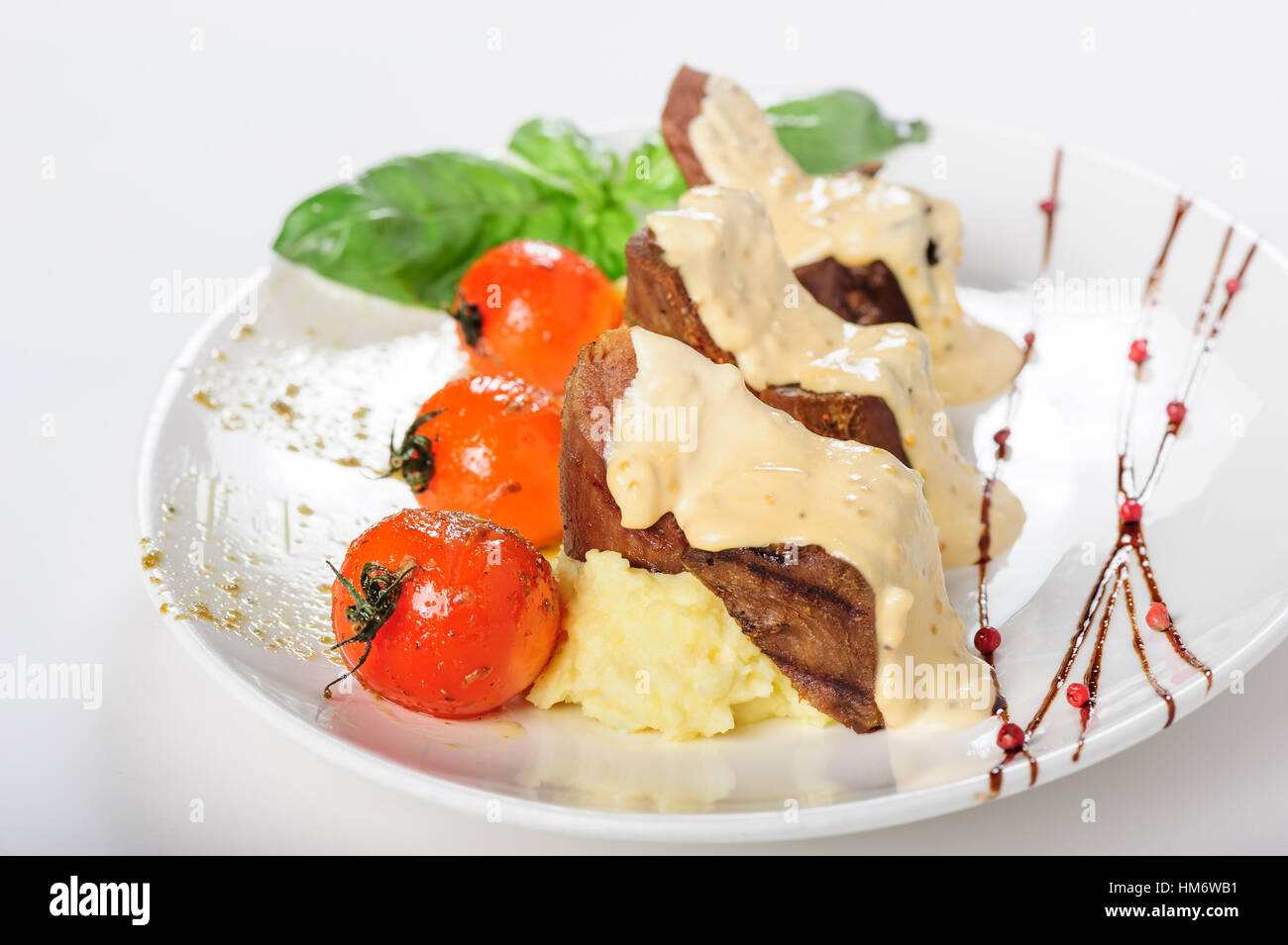 Gebackene Hammel Fleisch mit cremiger Sauce, Kartoffelpüree und Cherry-Tomaten Stockfoto