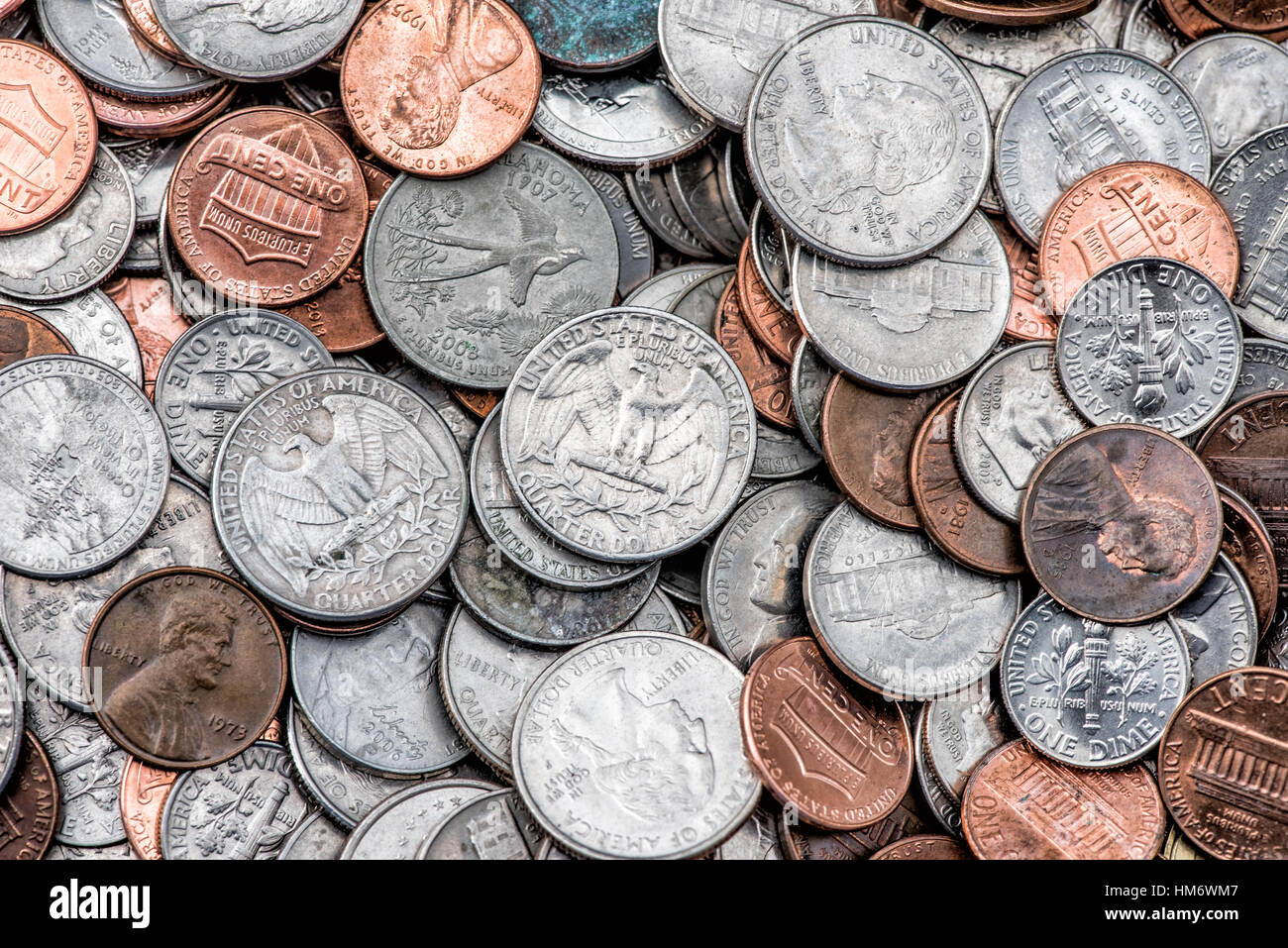 American Coins Quarters Dimes Pennnies United States // UNITED STATES — Ein verstreuter Stapel amerikanischer Münzen, darunter Quarter, Dimes, Nickels und Pennnies, zeigt die Vielfalt der US-Münzen im Umlauf. Die Viertel (25¢) weisen ihre markante Schilfkante und silberfarbene Cupronickel-Zusammensetzung auf, während kleinere Dimmen (10¢) eine ähnliche Färbung aufweisen, aber die Schilfkante fehlt. Kupferfarbene Pfennige (1¢) stehen im Kontrast zu den größeren nickelfarbenen fünf-Cent-Stücken und schaffen so eine vielfältige Palette von Stückelungen, die für den typischen Taschenwechsel im amerikanischen täglichen Handel stehen. Stockfoto