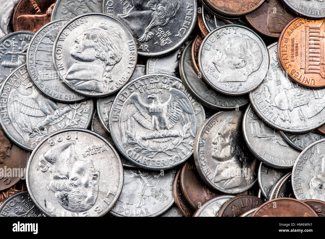 US-amerikanische Münzen Staufen Quarter Dimes Pennnies Vereinigte Staaten // VEREINIGTE STAATEN — Ein verstreuter Stapel amerikanischer Münzen, darunter Quarter, Dimes, Nickels und Pennnies, zeigt die Vielfalt der US-Münzen im Umlauf. Die Viertel (25¢) weisen ihre markante Schilfkante und silberfarbene Cupronickel-Zusammensetzung auf, während kleinere Dimmen (10¢) eine ähnliche Färbung aufweisen, aber die Schilfkante fehlt. Kupferfarbene Pfennige (1¢) stehen im Kontrast zu den größeren nickelfarbenen fünf-Cent-Stücken und schaffen so eine vielfältige Palette von Stückelungen, die für den typischen Taschenwechsel im amerikanischen täglichen Handel stehen. Stockfoto